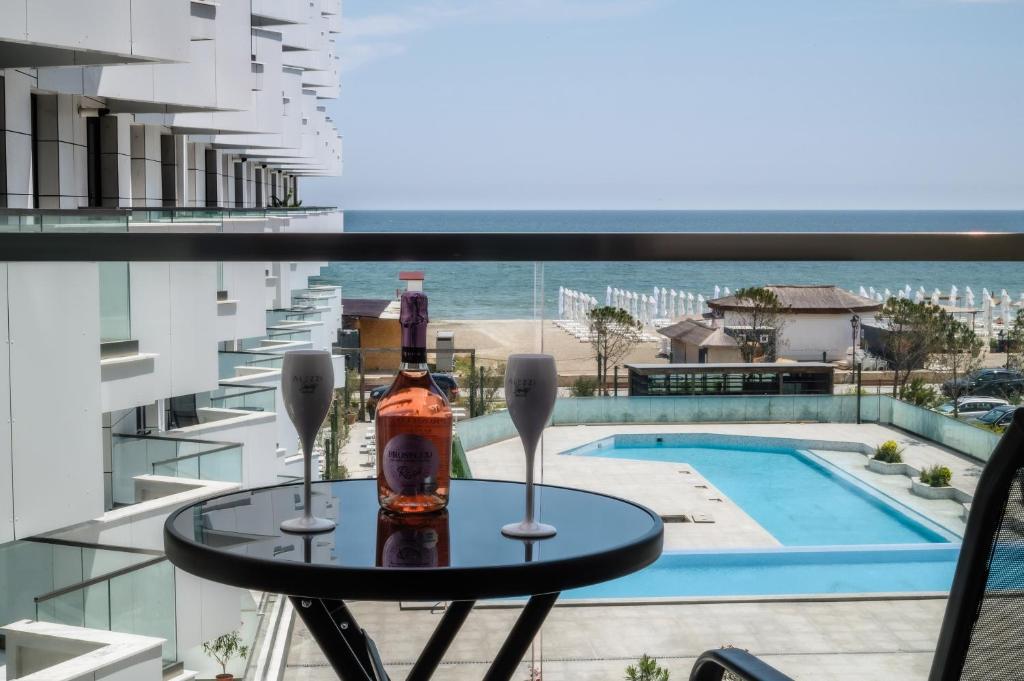 北马马亚-讷沃达里RoseBay std - Infinity Pool & Spa Resort的一个带游泳池的阳台的桌子和一瓶葡萄酒
