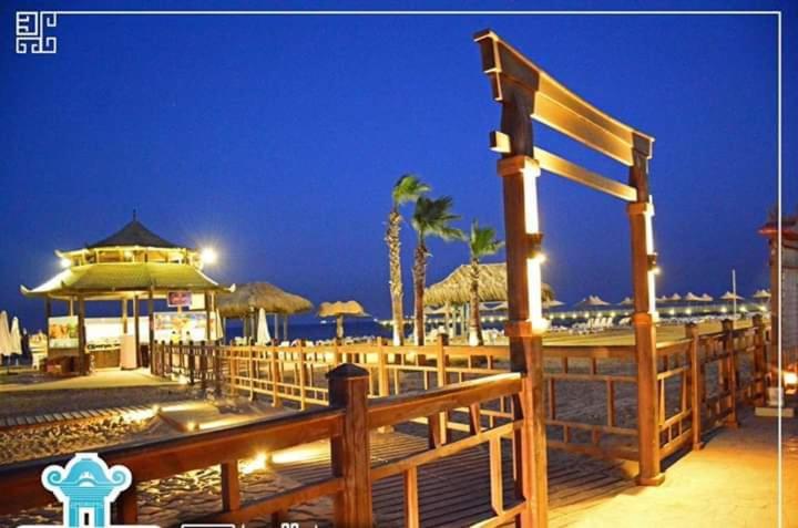 艾因苏赫纳فيلا في بلو باي أسيا العين السخنة的夜间海滩上带遮阳伞的木板路