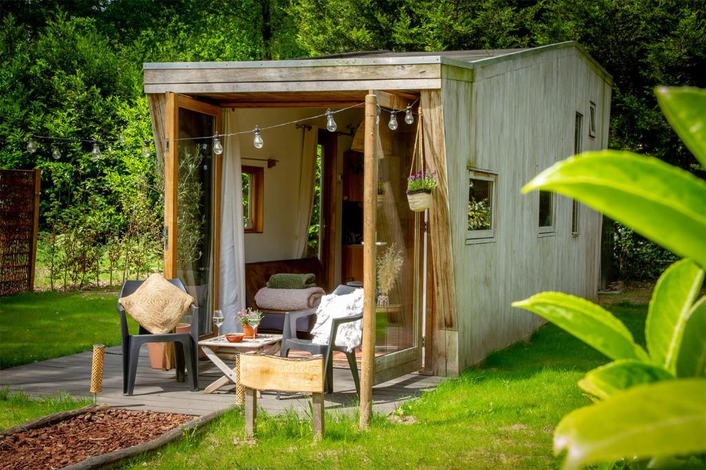 迪森Tiny House Hilver - uniek en sfeervol huisje middenin het bos的院子里带桌椅的棚屋