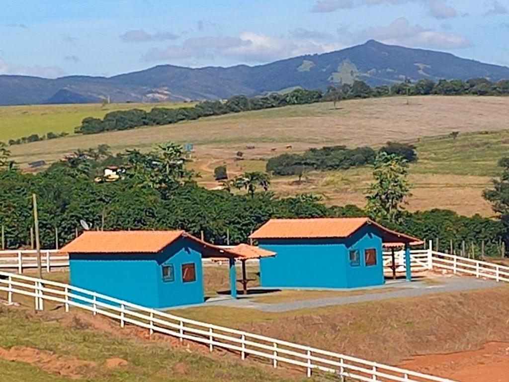 圣托梅-达斯莱特拉斯Chales Horizonte das Pedras的围栏旁的两座蓝色建筑