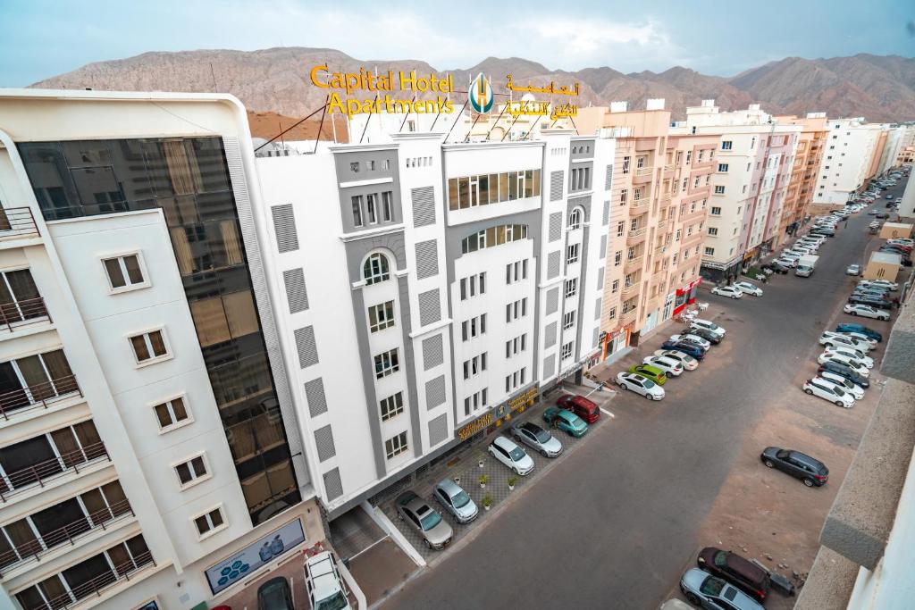 马斯喀特العاصمة للشقق الفندقية - Capital Hotel Apartments的享有大型白色建筑空中景色,设有停车场