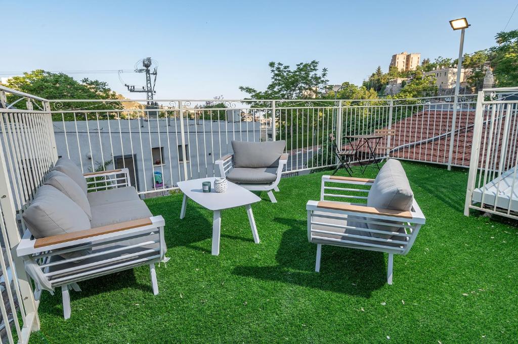 萨法德Moses Luxury Vacation Homes הבית בכ"ה的天井配有三把椅子和一张桌子,位于草地上