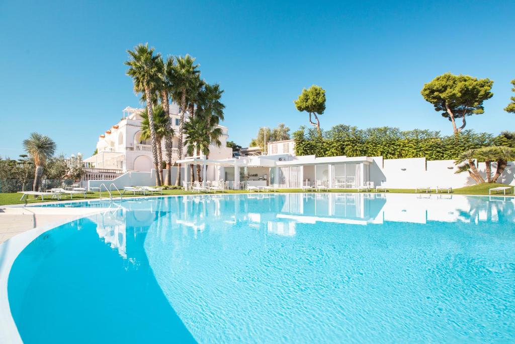 维耶斯泰Villa Coppitella, rooms & apartments的一座棕榈树大型游泳池和一座房子