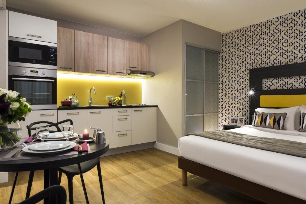 巴黎馨乐庭巴黎埃菲尔铁塔酒店的一间卧室配有一张床铺和一张桌子,还设有一间厨房