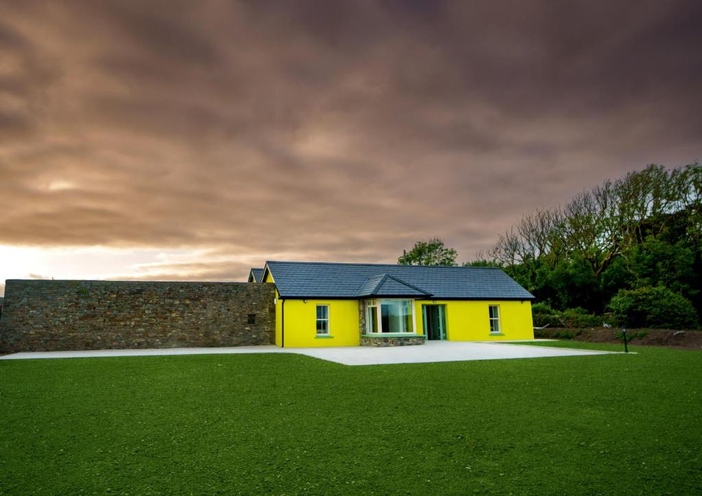 BallylongfordCarrig Island Lodge的黄色的房子,有墙和绿色的田野