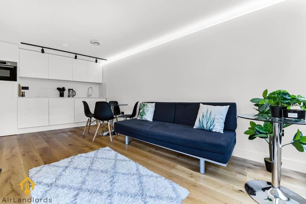 伦敦Charming Modern Chic Pad Summer House的客厅配有蓝色的沙发和地毯。