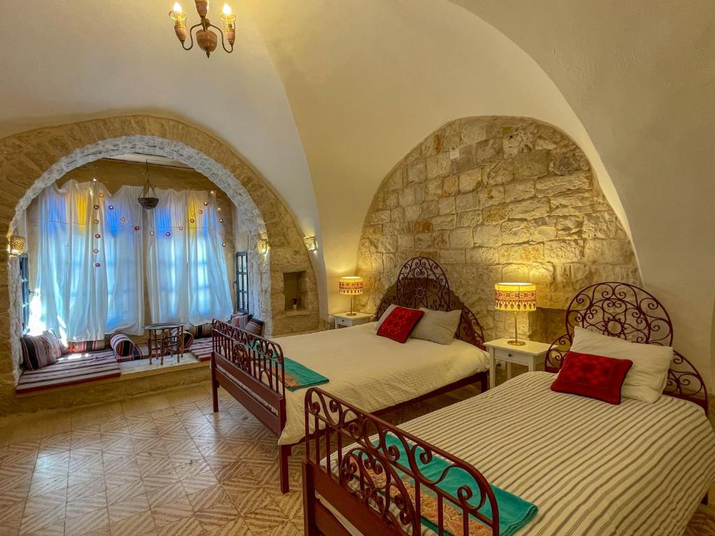 伯利恒Dar al Majus的一间卧室设有两张床和石墙