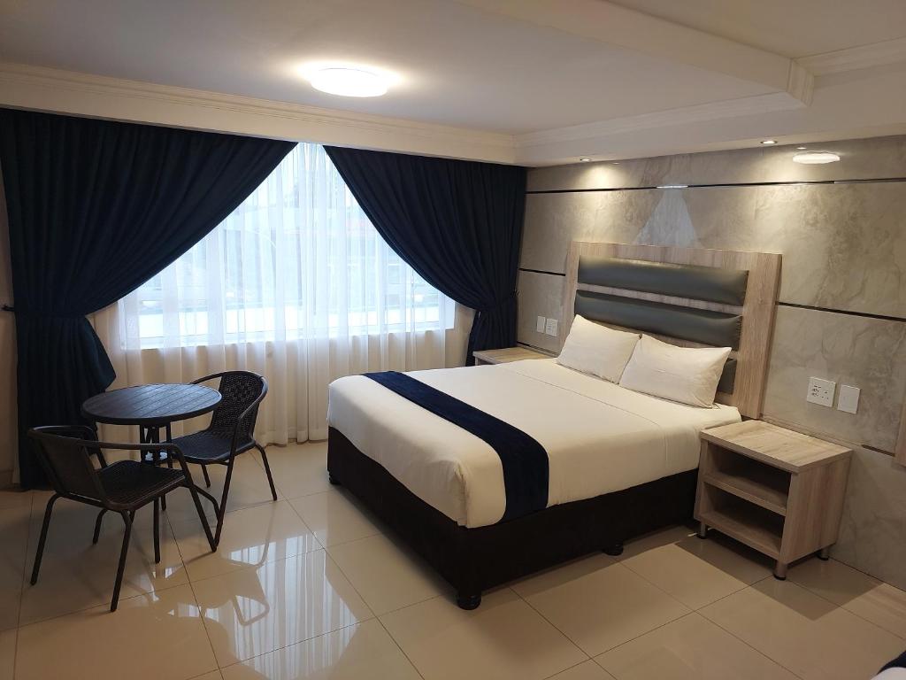 谢普斯敦港Bayside Taj Hotel的酒店客房带一张床、一张桌子和椅子