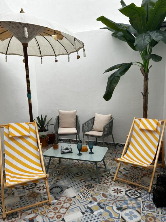 阿尔么丽亚Doña Josefina y Don Simón的庭院配有两把椅子、一张桌子和一把遮阳伞