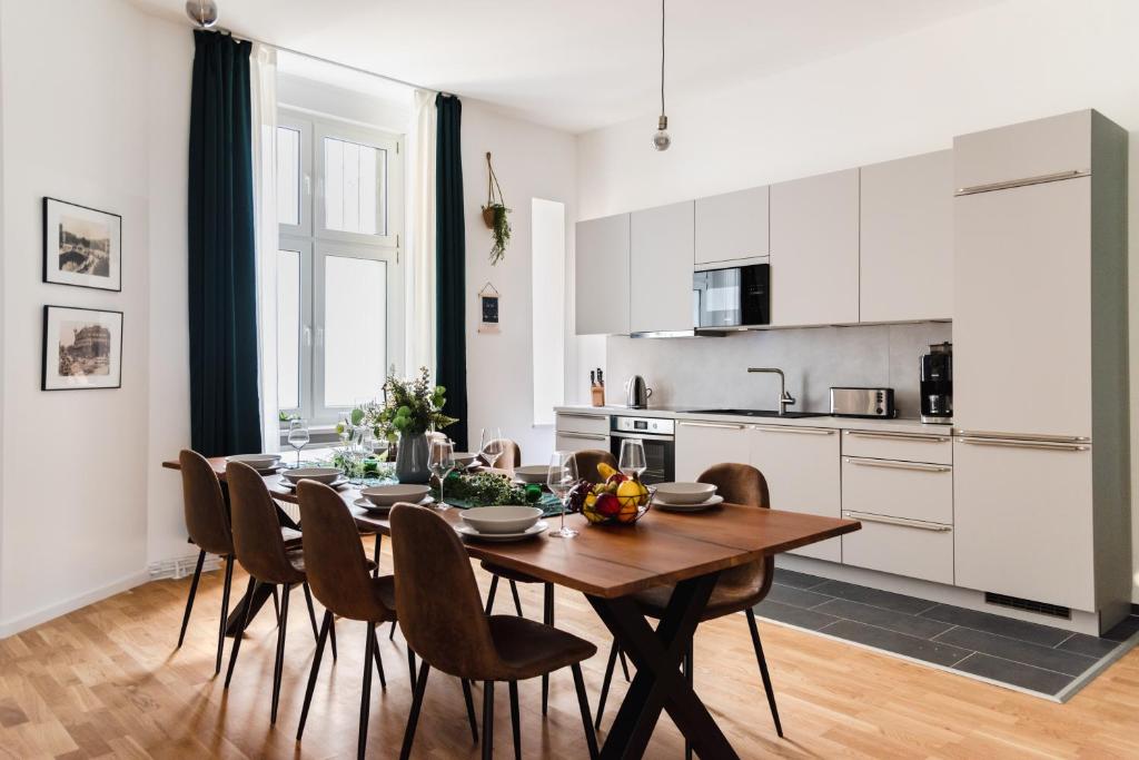 柏林165m2 Downtown Family Suite 5BR, 3Bath, kids room, 11min Alexanderplatz的厨房以及带木桌和椅子的用餐室。