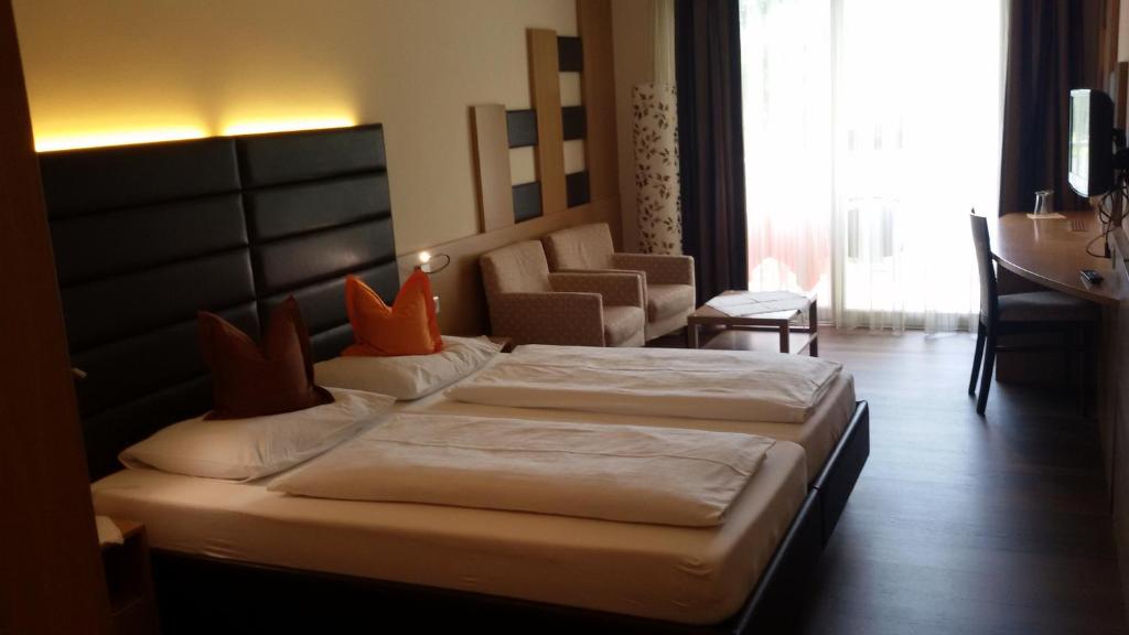 梅拉诺迈克西米利安酒店的酒店客房,配有两张床和椅子