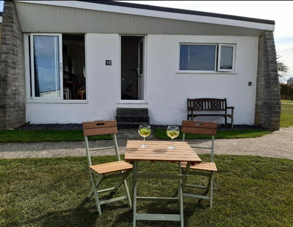 布德Chalet 18 Widemouth Bay Holiday Village的坐在房子前面桌子上的两杯酒