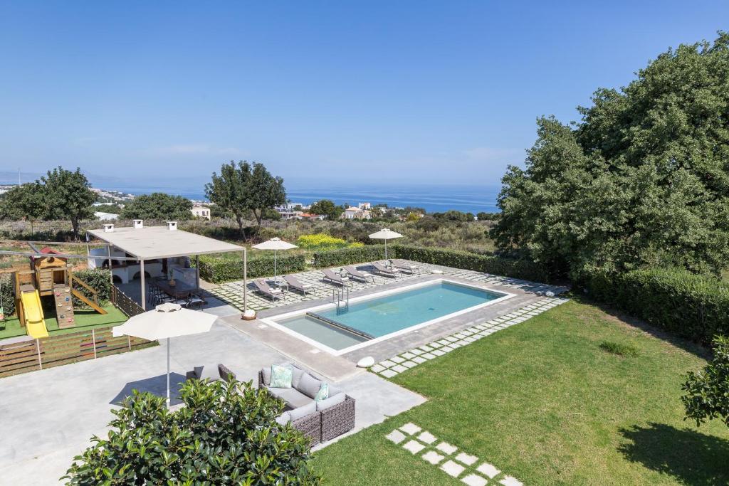 Mikro MetochiLux Villa Mia with Heated Pool, 2km to Beach & Childrens Area!的后院设有游泳池和带遮阳伞的草坪。