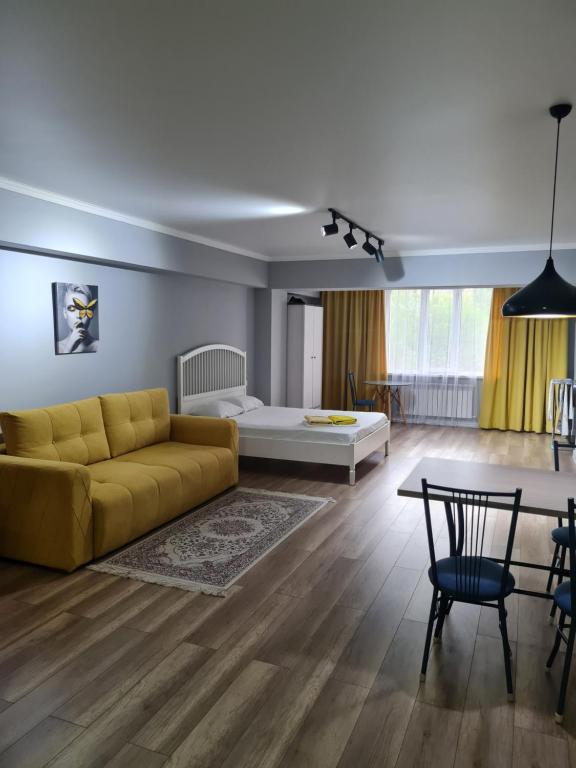 阿拉木图Апартаменты в центре, в новом доме的客厅配有黄色的沙发和桌子