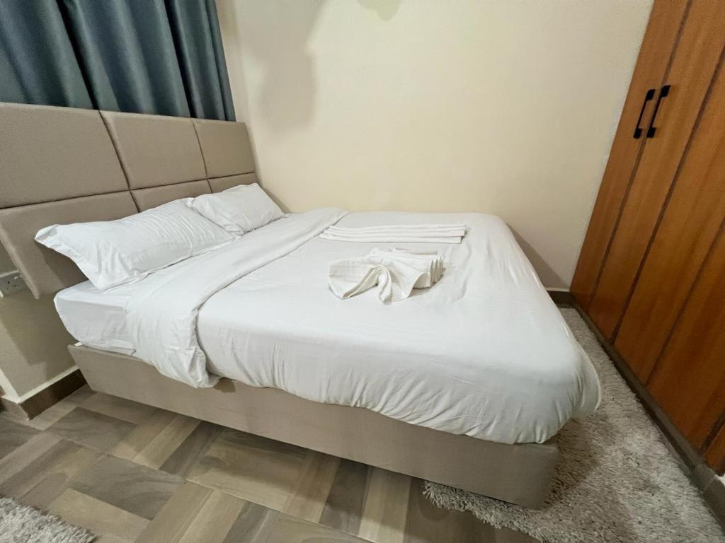 纳库鲁Urbantech 1 Bedroom Luxurious BnBs'的一张带白色床单的床和浴袍