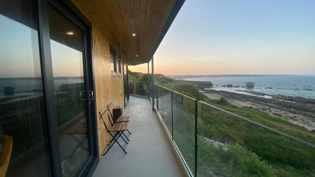 柯科迪Luxury beach front rooms- PMA的阳台,带两把椅子的建筑和大海