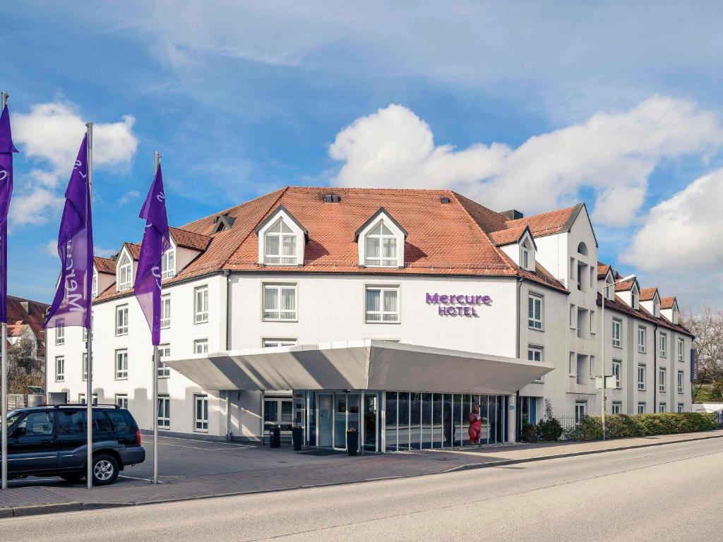 弗赖辛慕尼黑机场弗莱辛美居酒店 的前面有紫色旗帜的大型白色建筑