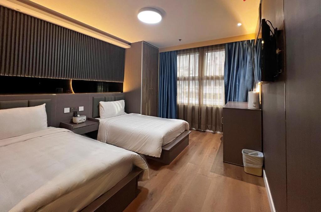 香港Hennessy Hotel的酒店客房设有两张床和电视。