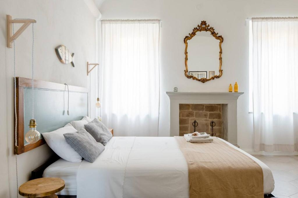 蒙特奇奥艾米利亚La Casa sulle Mura的白色卧室设有一张大床和镜子