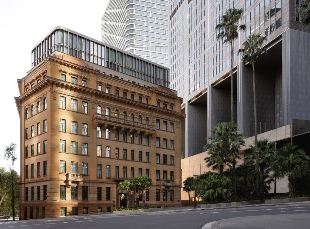 悉尼Capella Sydney的一座棕榈树环绕的建筑,位于高楼前