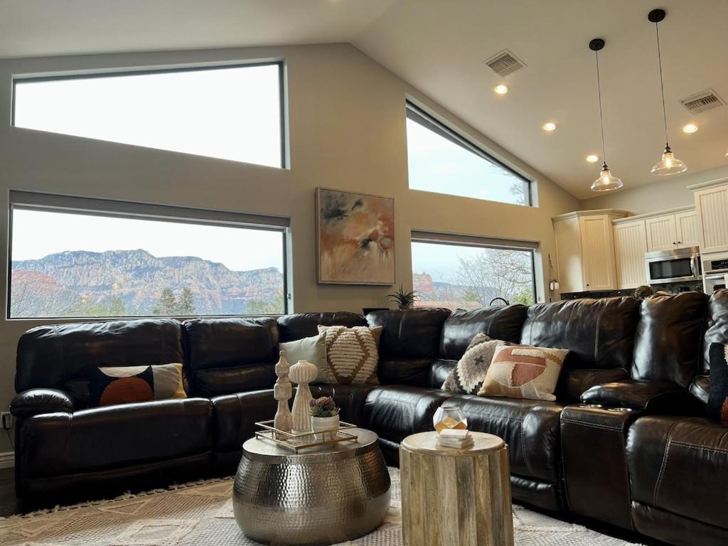 塞多纳Sedona Uptown Gem! Wow! Views!! NEW! BARREL SAUNA!!! Close to trails, walk to Uptown Sedona, restaurants and shopping的客厅设有一张黑色皮沙发,配有两个窗户