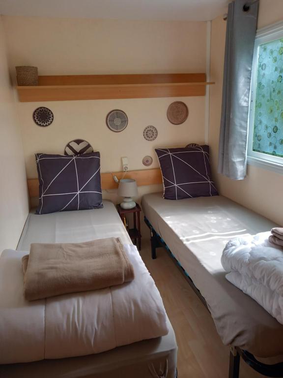 萨尔拉拉卡内达Mobile home au camping les Tilleuls du Caminel的客房配有两张带紫色枕头的床和窗户。