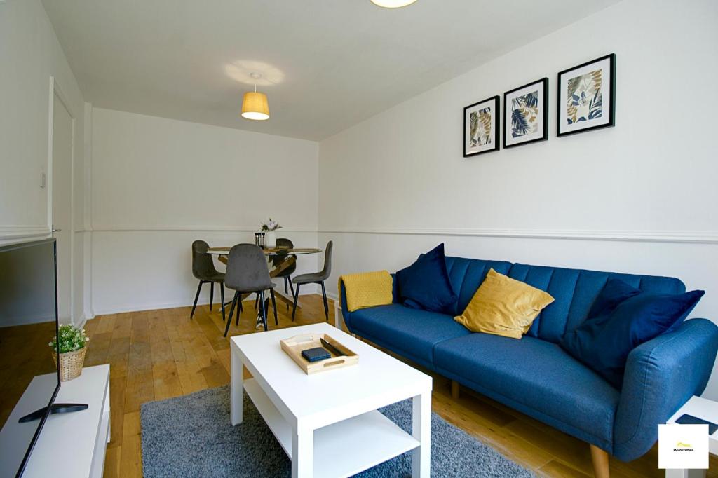 弗里姆利Camberley Spacious and Comfy 3 Bedroom Home, Next to Frimley Hospital with Parking的客厅配有蓝色的沙发和桌子