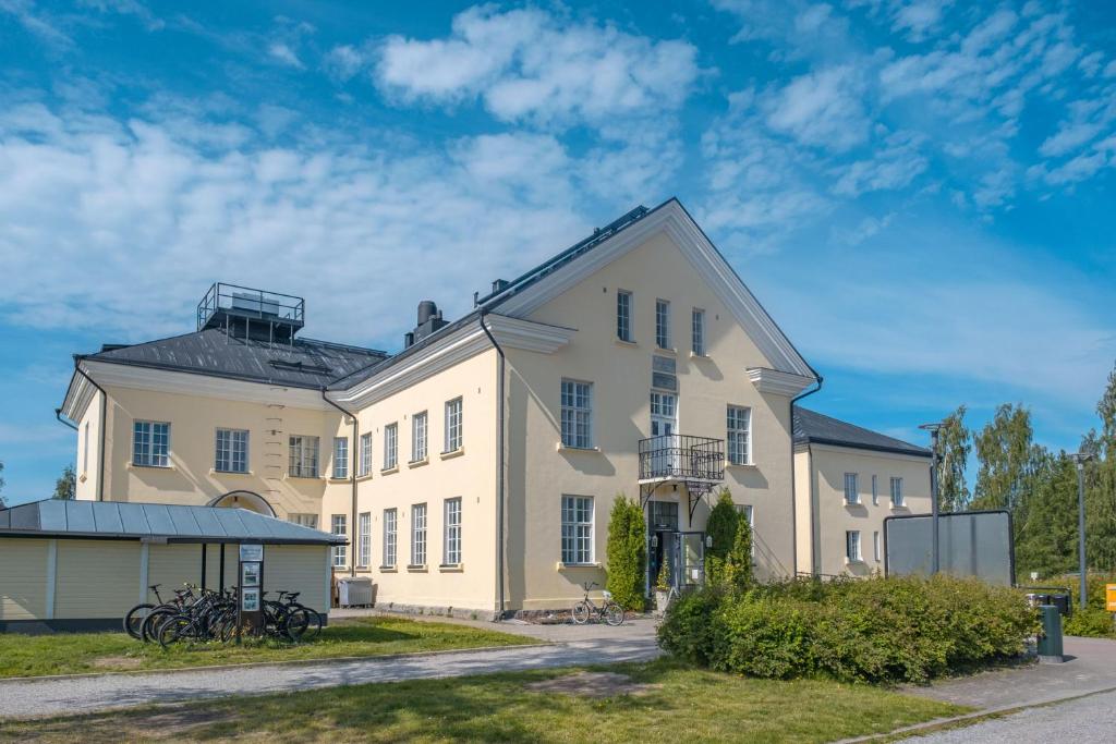 努尔梅斯Hyvärilä Youth- and Holiday Centre的一座白色的大建筑,前面有自行车停放