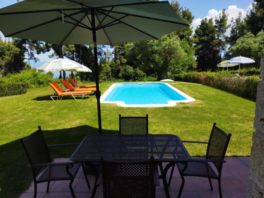 克里皮吉Stone Made Private Pool Villas Kriopigi的桌椅、遮阳伞和游泳池