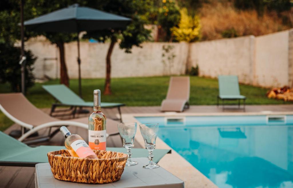 蓬德利马Villa Henriques的游泳池畔的桌子上放一瓶葡萄酒和玻璃杯