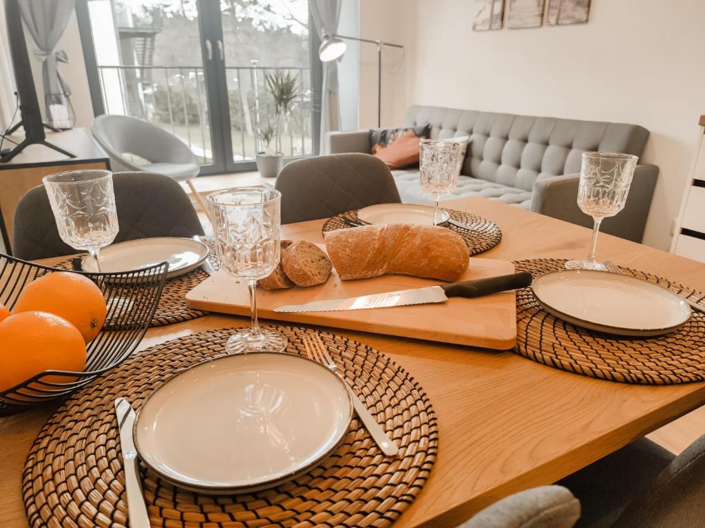 ĶesterciemsBeautiful Seaside apartement Albatross 24的一张木桌,上面有盘子和玻璃杯,还有面包