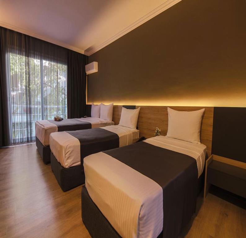 切什梅Grand Faik Hotel的酒店客房设有三张床和窗户。