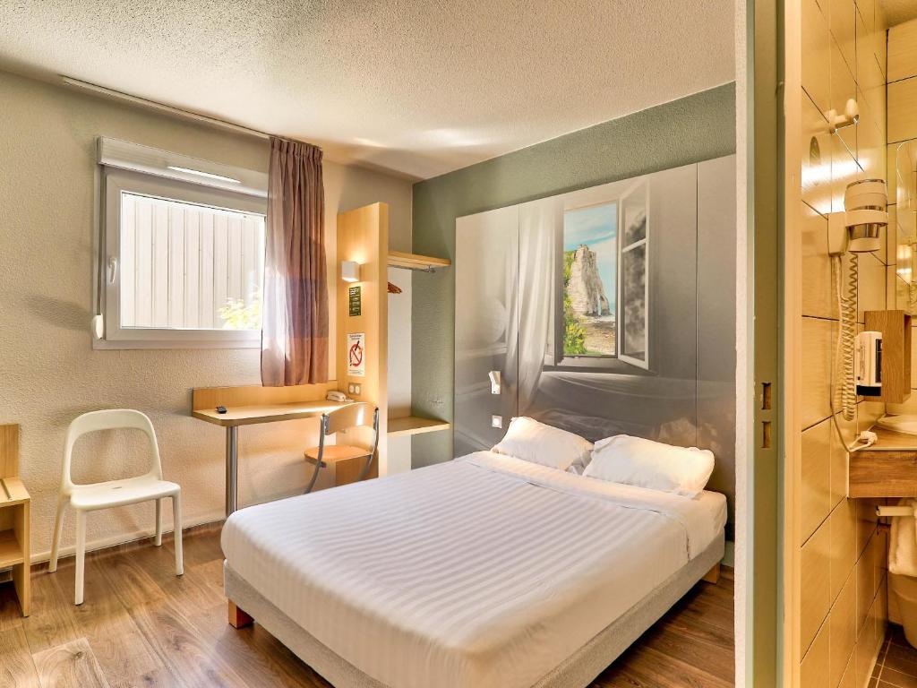 奥比埃B&B HOTEL Clermont-Ferrand Sud Aubière的配有一张床、一张书桌和一扇窗户的酒店客房
