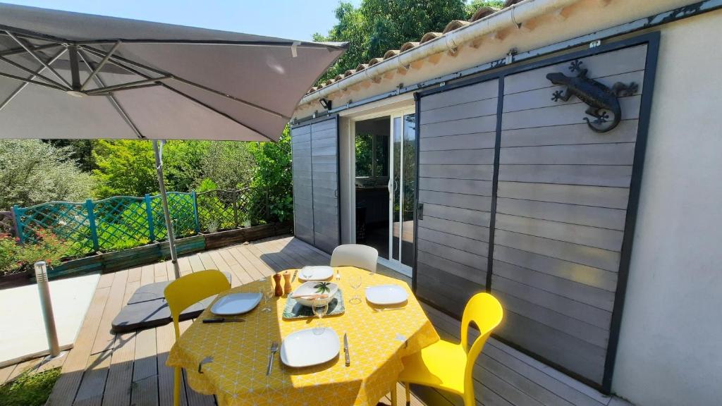 CrosGîte avec piscine et jacuzzi partagés en Cévennes的甲板上配有黄色的桌子和椅子,配有雨伞