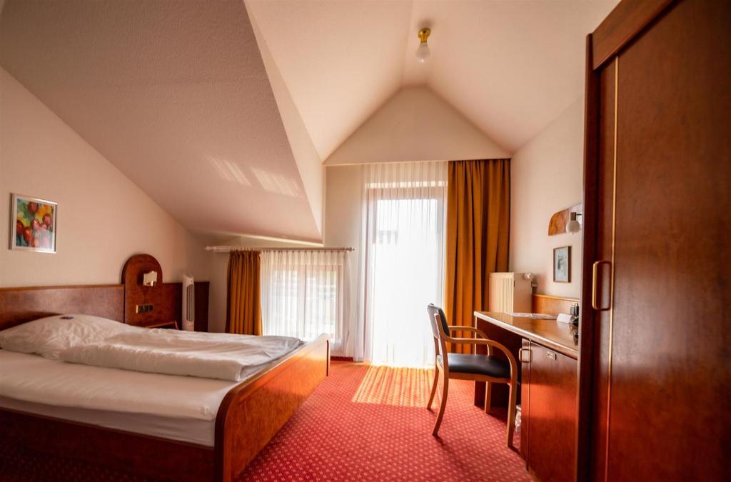 菲尔恩海姆Hotel Post Viernheim UG的配有一张床和一张书桌的酒店客房