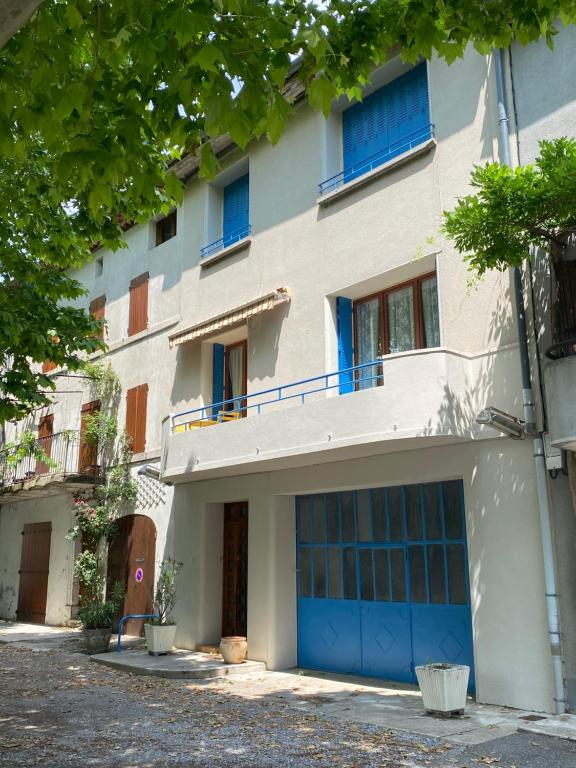 JaujacNOUVEAU Maison de la place的公寓大楼拥有蓝色的车库门和树木