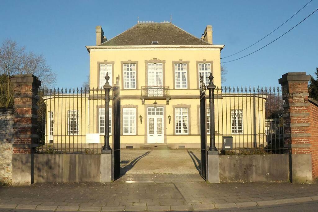 BeloeilPetit château à la campagne.的一座黄色的大房子,前面有栅栏