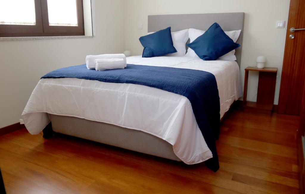埃斯平霍Cabo do Mar Apart.- Sereias Beach的一张大床,配有蓝色和白色的床单和蓝色的枕头