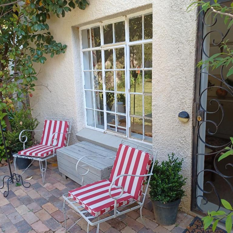 约翰内斯堡Craighall Park Stylish Garden Studio的窗前两把红白椅子