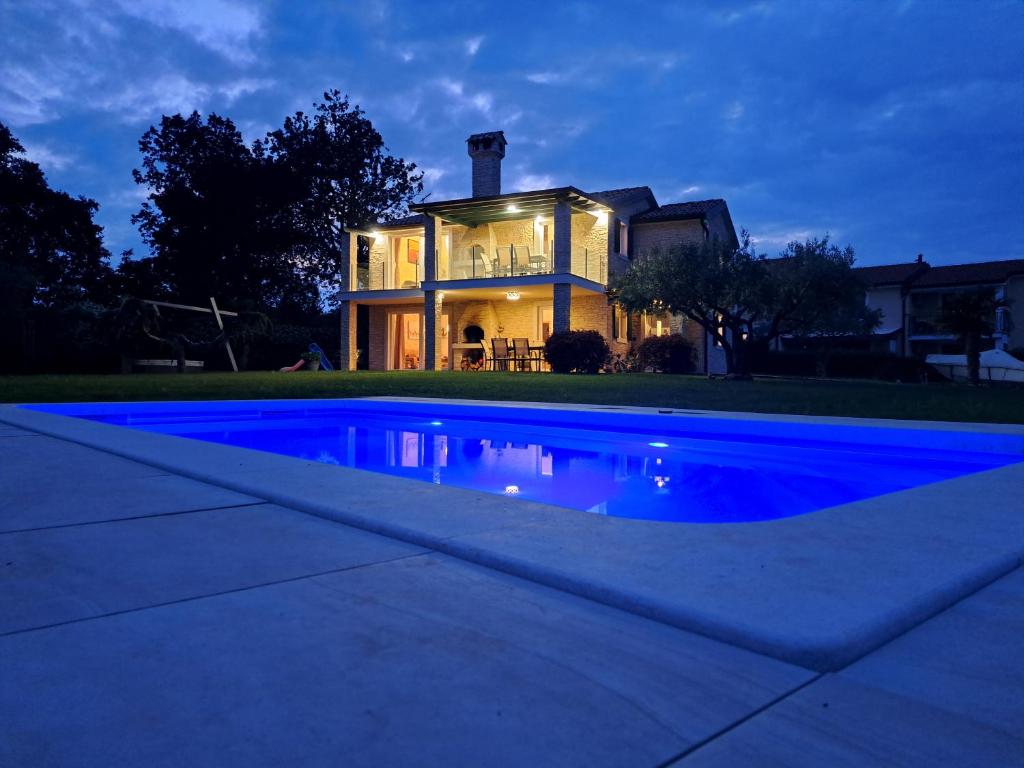 乌马格Apartments Villa Sotlar with pool的房屋前有蓝色游泳池的房子