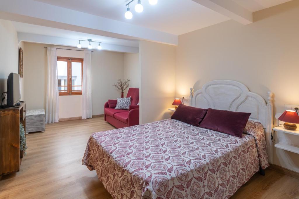 里瓦德塞利亚Belmonte, apartamento en Ribadesella的一间卧室配有一张床和一张红色椅子
