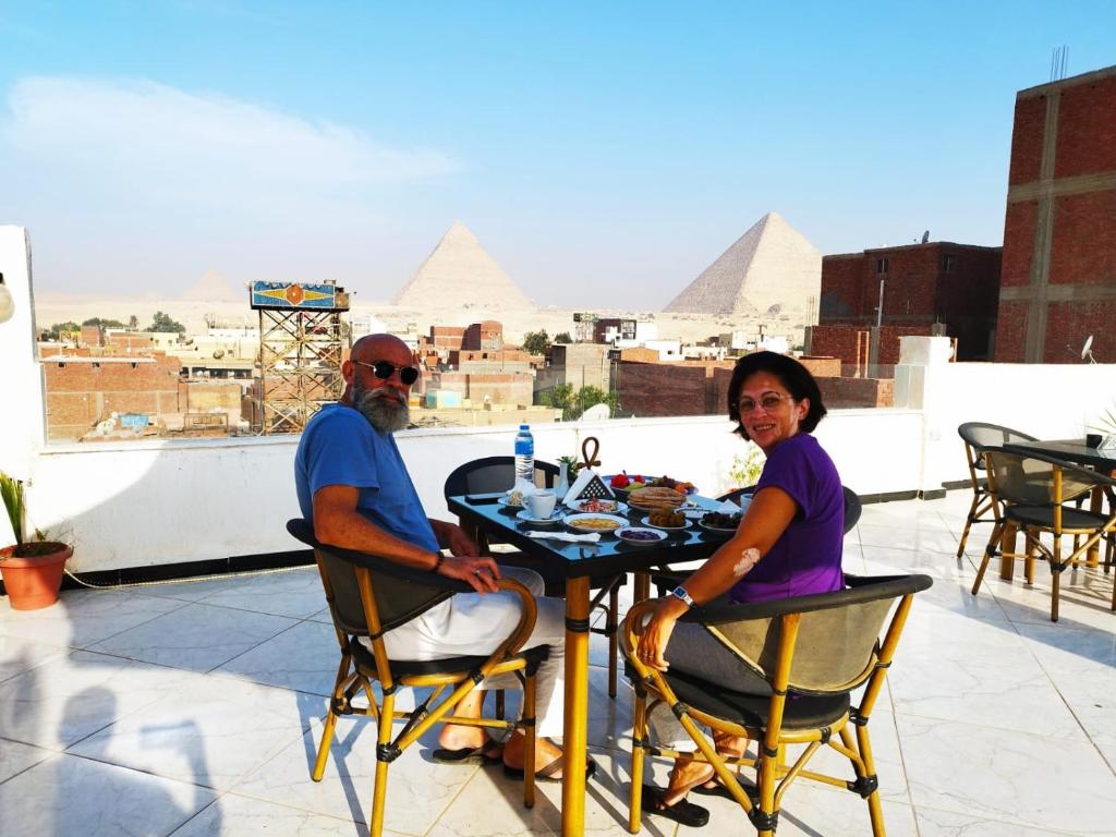 开罗Eagles Pyramids View的坐在有金字塔的桌子上的男女