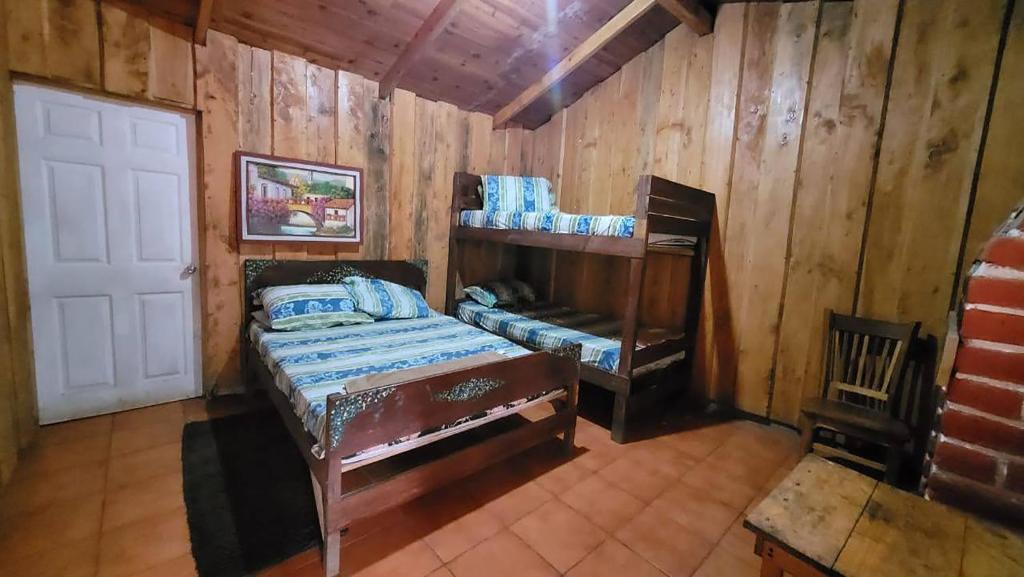 Río ChiquitoHotel de Montaña Buena Vista的木制客房内的1间带1张双层床的卧室