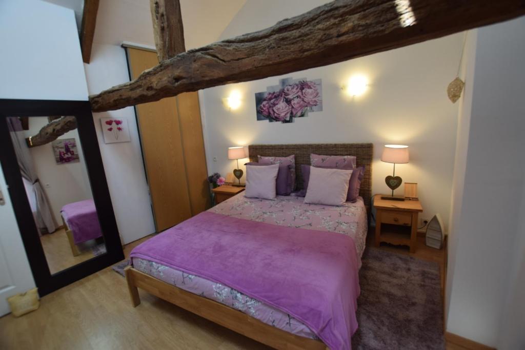 Le TeilleulLa libellule argentée的一间卧室配有一张带紫色床单的大床