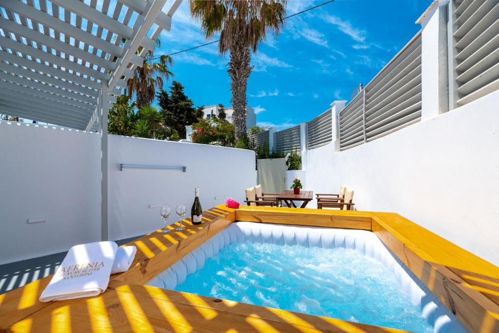 卡特瑞杜斯Aerenia Luxury Suites的一座游泳池,旁边是一座建筑,设有黄色长凳