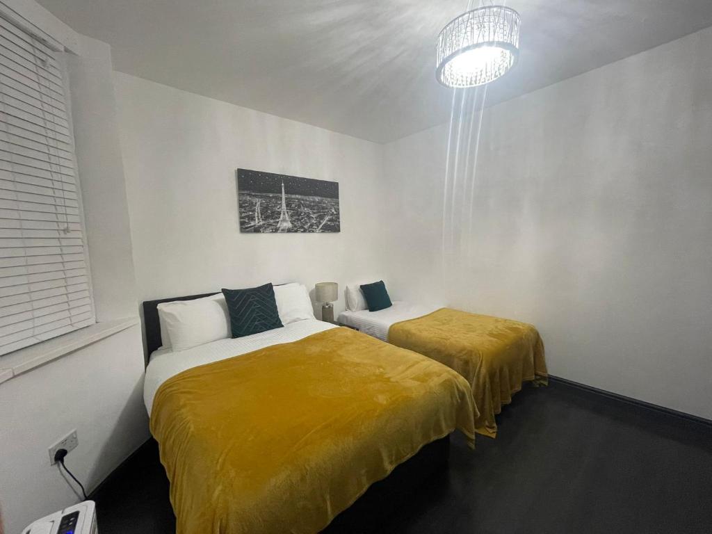 曼彻斯特Luxury Holiday Home的一间卧室配有两张带黄床单和吊灯的床。