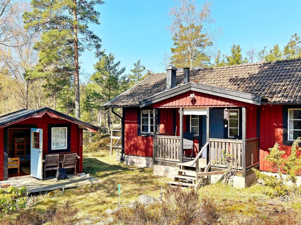 DalaröHoliday home ORNÖ II的树林中的红色小屋,设有门廊