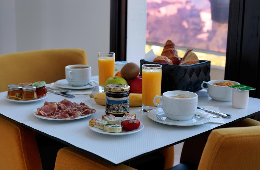 皮亚纳Hôtel Mare E Monti的早餐桌,包括早餐食品和橙汁