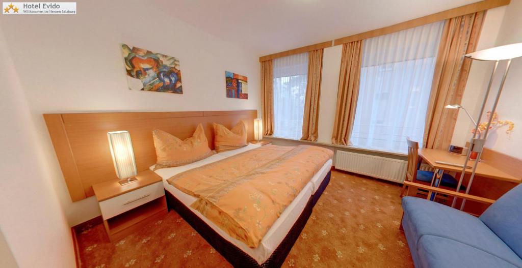 萨尔茨堡萨尔茨堡市中心伊维多酒店的一间卧室配有一张床和一张蓝色的沙发