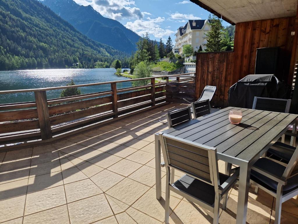 尚佩克斯Superbe appartement Champex-Lac avec piscine et sauna的湖景甲板上的桌椅